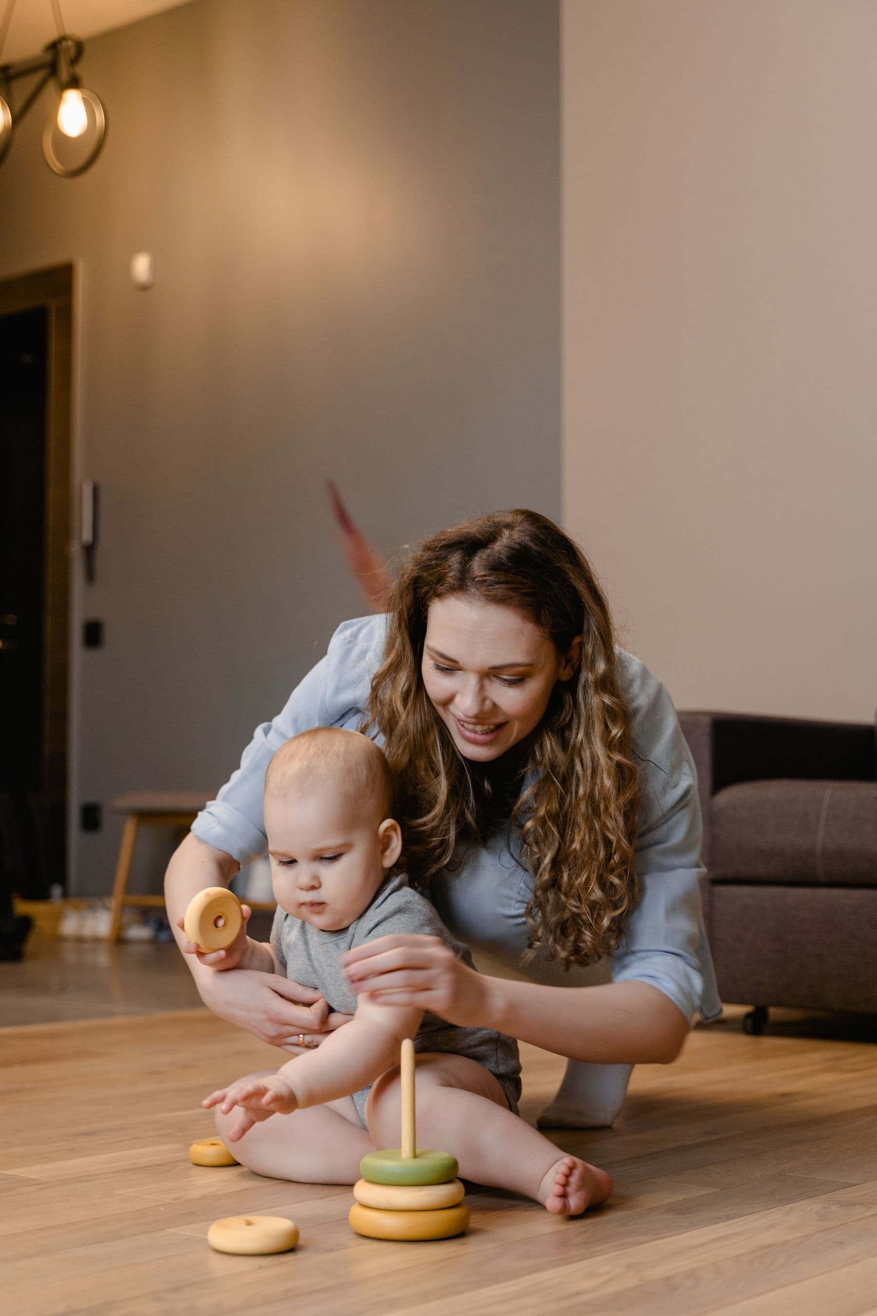 A nanny playing with a baby on the living room floor